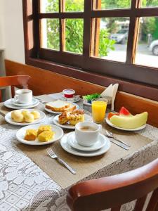 a table with plates of breakfast food on it at Hotel Pousada Garoupas in São Sebastião