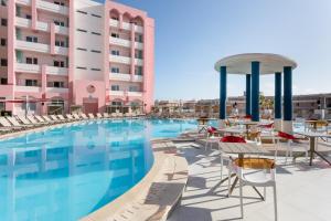 a swimming pool with chairs and tables next to a building at Vegas Resort in St. Julianʼs