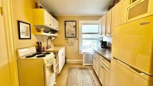 a yellow kitchen with a stove and a refrigerator at Commanders Cabin, quaint apt steps to downtown in Camden