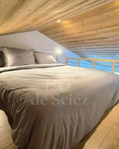 a large bed in a bedroom with a wooden ceiling at L'Ô de Sciez in Sciez