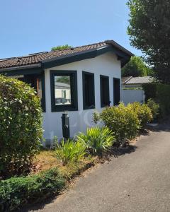 a small white house with black windows and bushes at L'Ô de Sciez in Sciez
