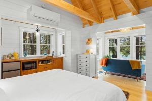 a white bedroom with a bed and a blue couch at Lindquist Cottage | Waterfront Studio with King Bed in Clark Island