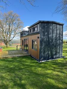 a tiny house with a black exterior in a field at Kniveton Wood Hut in Ashbourne