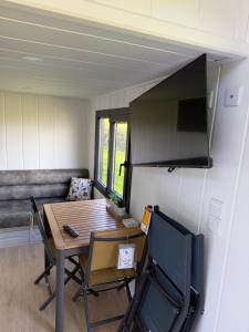 a small dining room with a table and a couch at Kniveton Wood Hut in Ashbourne