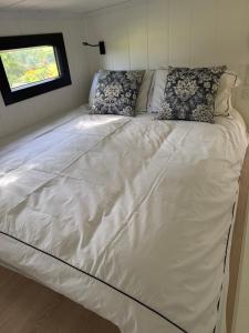 a large white bed in a tiny house at Kniveton Wood Hut in Ashbourne