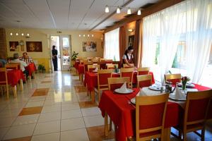 een restaurant met rode tafels en stoelen en een staande vrouw bij Hotel Clavis in Lučenec