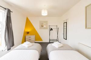 two beds in a room with a yellow and white wall at York House - Garston - 3 bedroom - Sleeps 6 in Liverpool