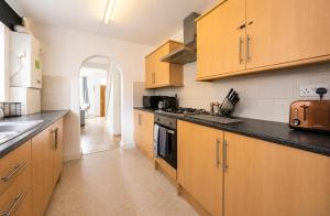 a kitchen with wooden cabinets and a black counter top at York House - Garston - 3 bedroom - Sleeps 6 in Liverpool