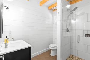 a white bathroom with a shower and a toilet at Lindquist Cottage | Waterfront Studio with King Bed in Clark Island