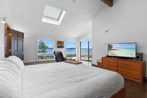 a white bedroom with a large bed and a television at Clark Point Cottage, ocean access, panoramic views in Clark Island