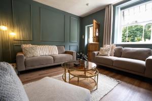 a living room with two couches and a glass table at Old Lumford Cottage, Bakewell - Picturesque Riverside Property in Bakewell