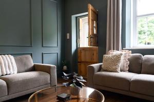 a living room with two couches and a glass table at Old Lumford Cottage, Bakewell - Picturesque Riverside Property in Bakewell