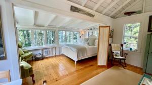 a bedroom with a bed in a room with windows at Whispering Spruces; Cozy Studio with Queen Bed & W in South Thomaston