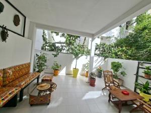 ein Balkon mit Couch, Tischen und Topfpflanzen in der Unterkunft Téranga Home Cosy & Spacieux à 600m de la plage in Dakar