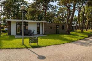 a small house with a sign in the grass at Cube & Quiet - Where nature meets comfort in Haarle