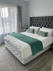 a bedroom with a large bed with a green blanket at House 22 on Alice in Centurion +17 photos