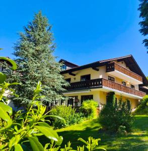 a large house with a tree in the yard at Frühstück Pension by Anna in Rattenberg