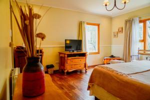 a bedroom with a bed and a tv and a vase with flowers at Nuevo Puerto Malen in Villa Pehuenia