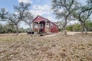 a red tiny house in a field with trees at Hill Country Cabin 3 in Canyon Lake