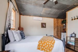 a bedroom with a white bed with an orange blanket at Hill Country Cabin 2 in Canyon Lake
