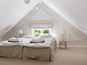 a white bedroom with a bed in a attic at 12 person holiday home in BÅSTAD-By Traum in Båstad +32 photos
