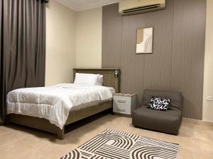 a bedroom with a bed and a chair at Stylish 2BR Escape Near Muscat City Centre in Mawāliḩ