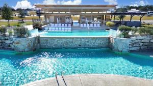an outdoor swimming pool with chairs and a building at Modern Tiny Home with Loft, Kitchen, Cozy Patio and Shared Pools, Great Location in Fredericksburg