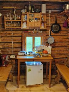 a kitchen with wooden walls and a table and a refrigerator at Guest house Oaze in Miglāni +42 photos
