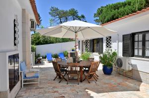 a patio with a table and an umbrella at Cottage Sete Mares in Colares