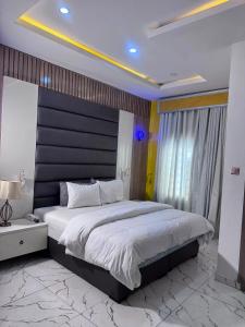 a bedroom with a large bed with a black headboard at Stone and Beam apartment in Abuja