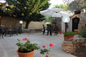 a patio with tables and chairs and an umbrella at Trullo Salento in Galatone +2 photos