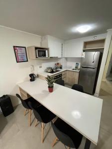 a kitchen with a white table and a refrigerator at Comodidad, descanso y disfrute in Algarrobo