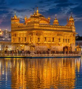 a large building sitting in the water at night at Hotel Nayyar Inn Near Golden temple in Amritsar