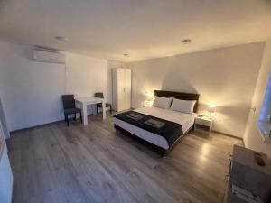 a bedroom with a bed and a table and a desk at Apartmani L&V in Kula