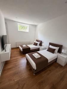 a bedroom with two beds and a television in it at Apartmani L&V in Kula