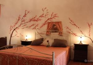 a bedroom with a bed with a tree on the wall at Trullo Salento in Galatone