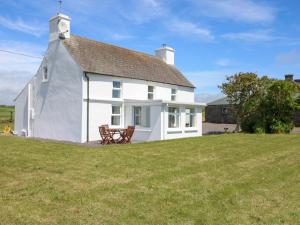 a white cottage on a hill with a bench at Teach Feirme in Clonakilty