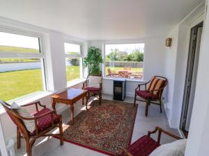 a living room with chairs and a table and windows at Teach Feirme in Clonakilty