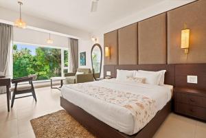 a bedroom with a bed and a desk and a chair at Verano Hotel & Spa Arpora Goa in Arpora