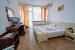 a bedroom with a bed and a desk and a television at Hotel Callatis in Neptun