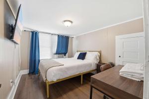 a bedroom with a bed and a table and blue curtains at Group-Ready 6BR Gem in Central Lafayette in Lafayette
