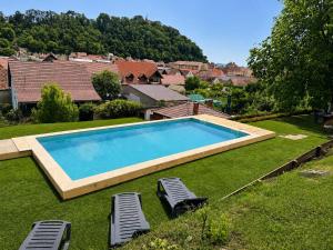 a swimming pool in a yard with two lawn chairs at Casa Adalmo in Sighişoara