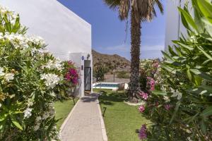 a garden with flowers and a palm tree and a building at Sunny Holidays Mojácar Pool House in Mojácar