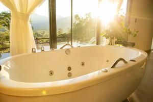 a white bath tub in a bathroom with a window at Encosta do Café - Chalé Oliveira in Itati +40 photos