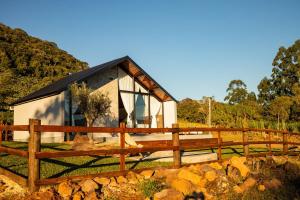 a house with a wooden fence in front of it at Encosta do Café - Chalé Oliveira in Itati