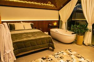 a bedroom with a bed and a bath tub in a room at Encosta do Café - Chalé Oliveira in Itati