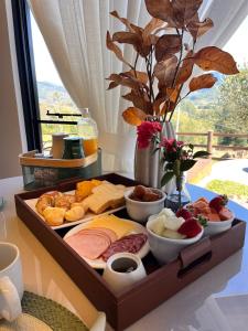 a tray filled with different types of food on a table at Encosta do Café - Chalé Oliveira in Itati