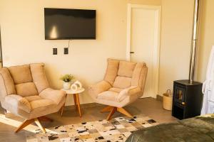 a living room with two chairs and a tv at Encosta do Café - Chalé Oliveira in Itati