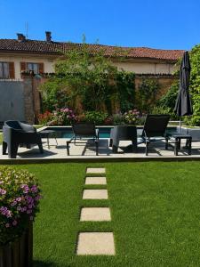 a garden with chairs and tables and an umbrella at Villa Lu alloggio con idromassaggio e piscina in Carignano