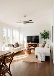 a living room with white furniture and a flat screen tv at Marshfront 5BD Oasis Pool Yard & Steps to Beach in Folly Beach